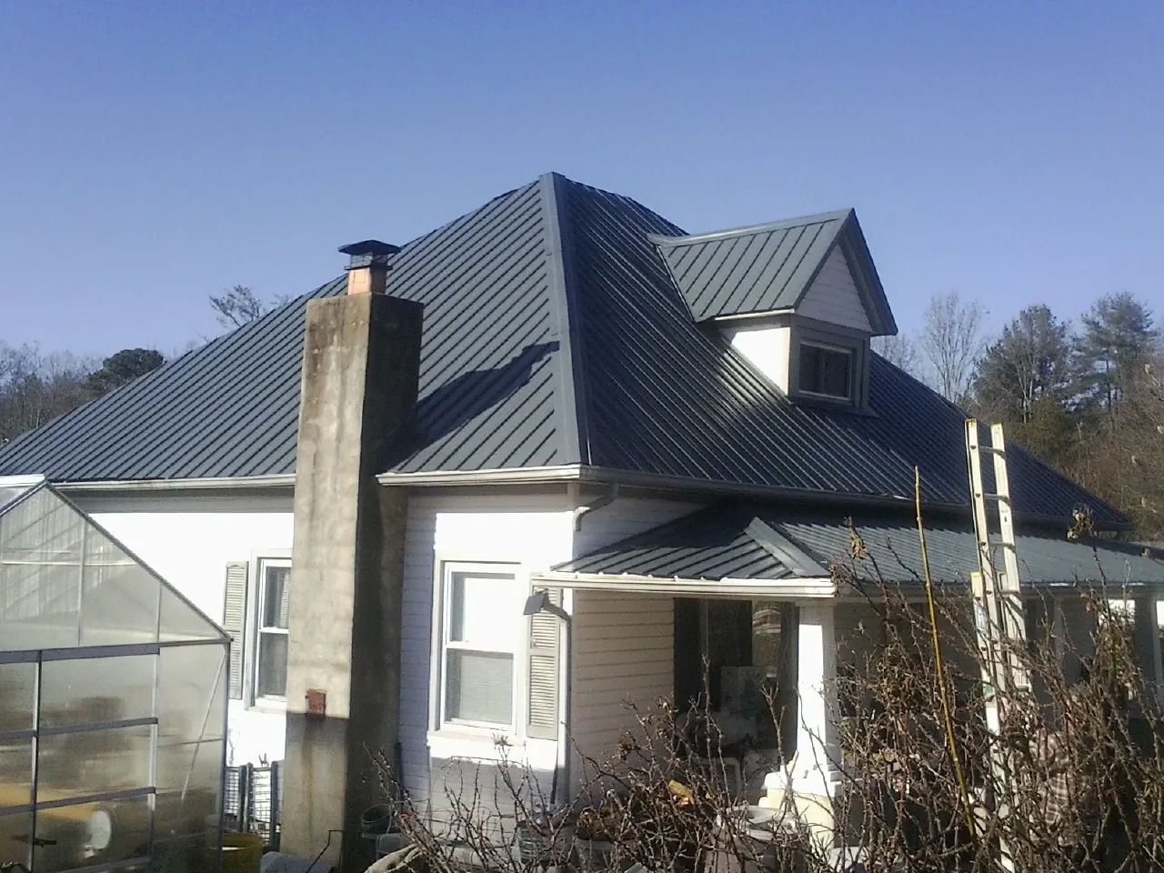 Dark blue standing seam metal roof on a white farmhouse with dormer — Slate & Tile Roof Repair by Roofing Brothers in Villa Rica