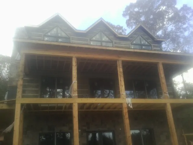 Dormers and porch framing on a large log home under construction — Roof Coating work by our crew in Villa Rica