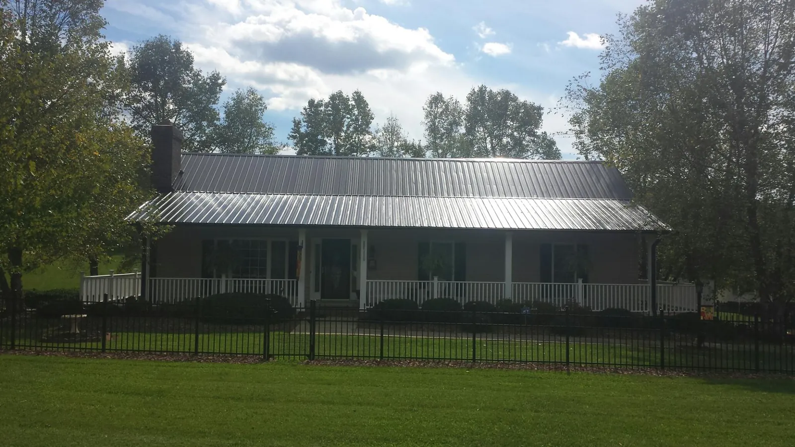 Gray metal roof on a brick ranch with a full width front porch — Gutter Guard Installation work by our crew in Villa Rica
