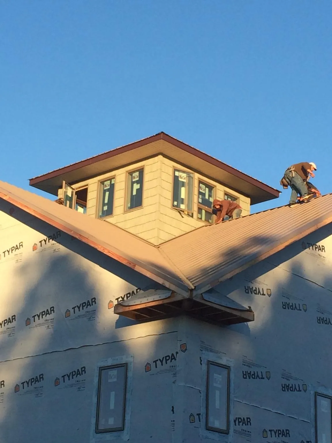 Roofers working around a rooftop cupola on a new metal roof at sunset — Roof Waterproofing in Villa Rica by Roofing Brothers